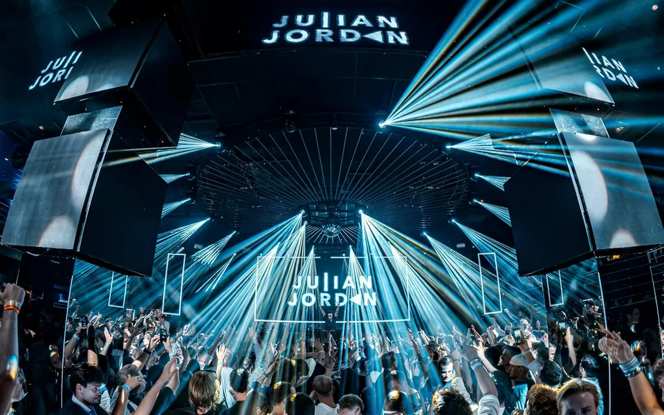 Palco DJ e fasci di luce sopra la folla del club