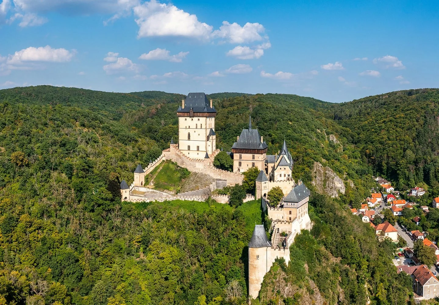 Karlštejn Castle rising above wooded hills