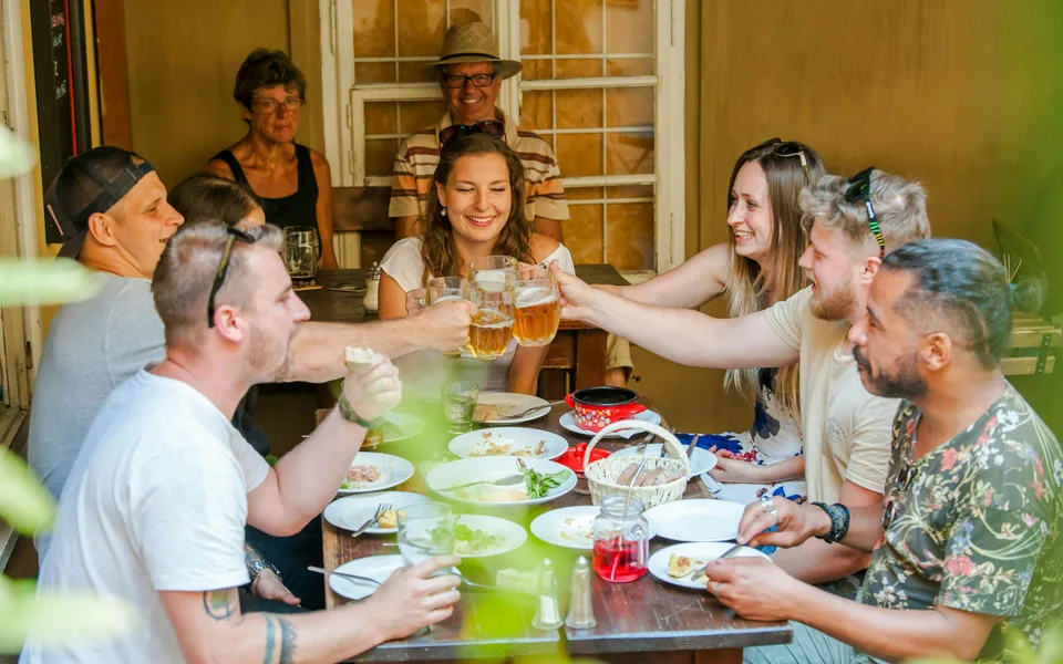 Visitors sharing food and beer at a Prague table