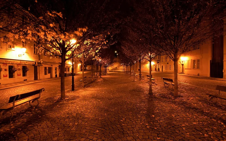 A cobbled Prague street lit by lamps at night