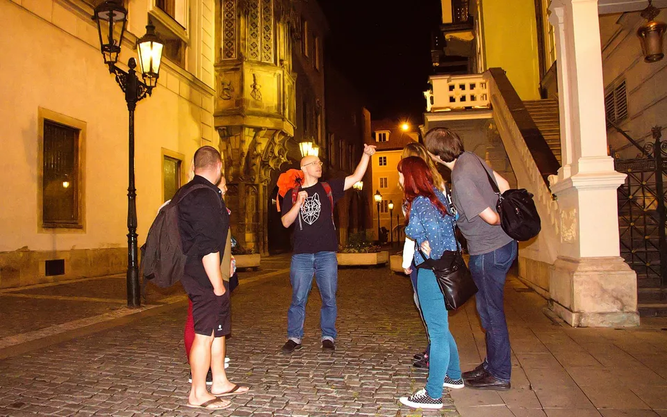 Guide and visitors on a Prague street after dark