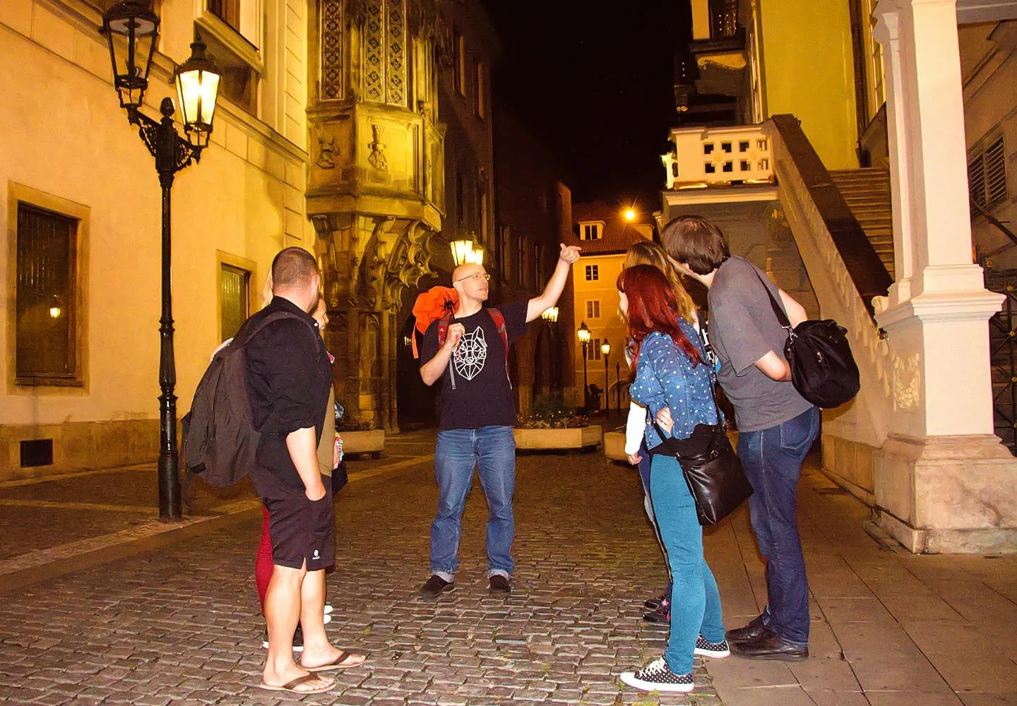 Guide and visitors on a Prague street after dark
