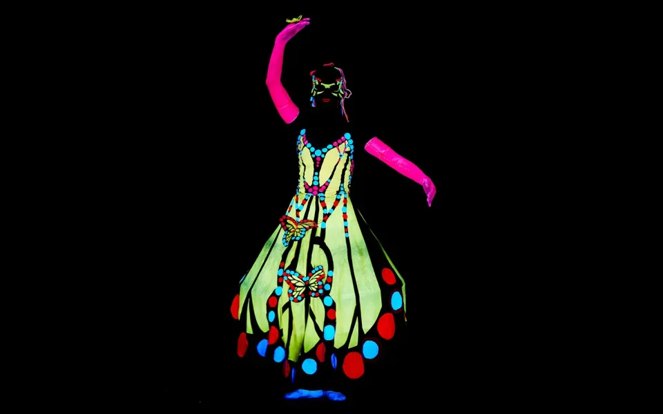 Performer in a fluorescent costume during a black light show