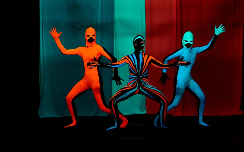 Performers in brightly coloured costumes at a black light theatre