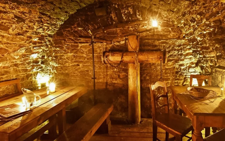 Rustic wooden seating beneath a vaulted stone ceiling in the tavern