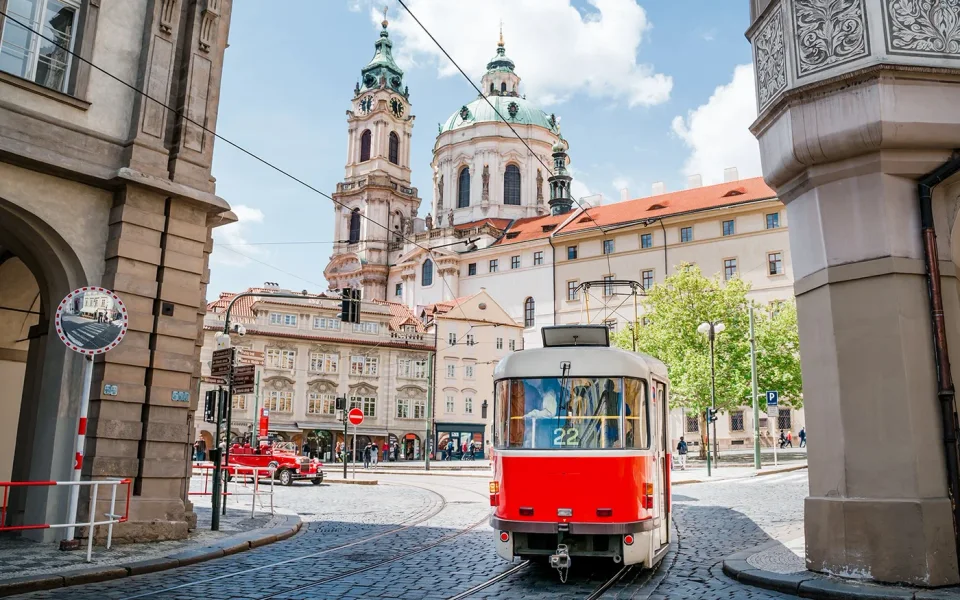 Red tram passing through an archway in Prague